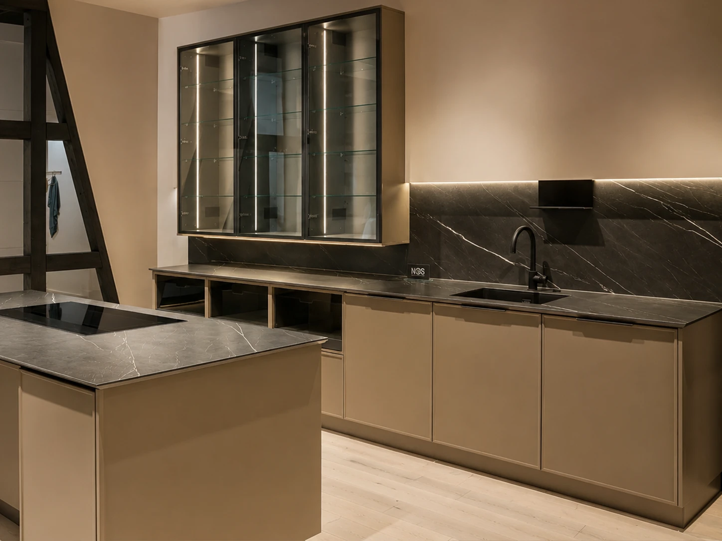 Cuisine Häcker beige taupe avec îlot central, plan de travail marbre noir veiné et plaque intégrée